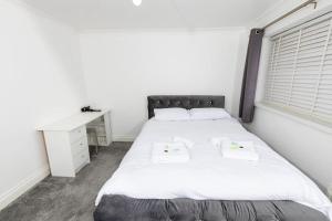 Schlafzimmer mit einem großen weißen Bett und einem Schreibtisch in der Unterkunft Comfy 2 Bedroom House for 4 in Strood