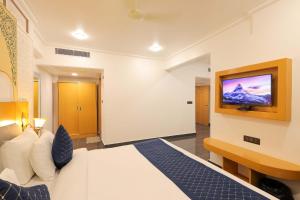 a bedroom with a bed and a tv on the wall at Hotel Ganga Ratan in Agra