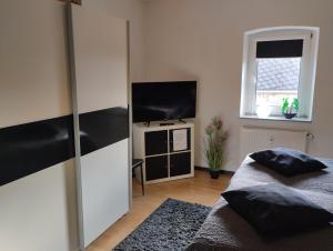 a bedroom with a bed and a flat screen tv at Ferienwohnung Am Vulkanpfad in Ettringen