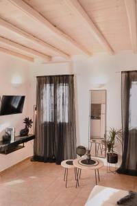 una sala de estar con cortinas y mesas negras. en NISOS Home Stay, en Mykonos ciudad