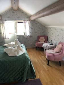a bedroom with two beds and two pink chairs at Mysigt HÄRBRE STUGA med utsikt över Siljan in Rättvik