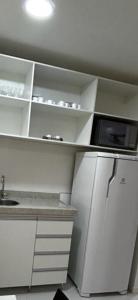 uma cozinha branca com um micro-ondas e um frigorífico em VISION Flat Particular Varanda Garagem Piscina Academia em Brasília