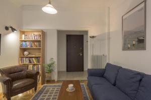 uma sala de estar com um sofá azul e uma cadeira em Arktinou apartment em Atenas