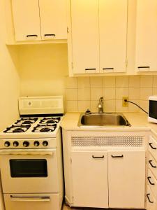 een witte keuken met een fornuis en een wastafel bij Stylish Montreal Apartment: Comfortable Stay in the Golden Square Mile in Montreal