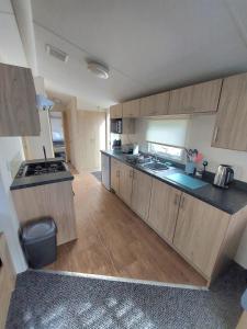 a large kitchen with wooden cabinets and a sink at Haven holiday park Cleethorpes beach in Cleethorpes