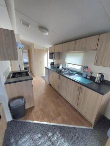 a large kitchen with wooden cabinets and a sink at Haven holiday park Cleethorpes beach in Cleethorpes +11 photos