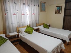 a room with three beds with white sheets and green pillows at RESIDENCIA-UNIV in Ciudad del Este