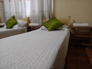 a bedroom with a white bed with green pillows at RESIDENCIA-UNIV in Ciudad del Este