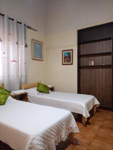 two beds in a hospital room with white sheets at RESIDENCIA-UNIV in Ciudad del Este