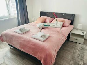 a bedroom with a pink bed with two towels on it at Apartment Zara Bihac in Bihać