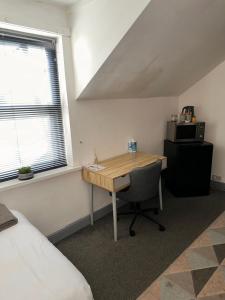a small room with a desk and a microwave at P&S rooms guesthouse Lincoln city centre in Lincolnshire