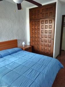 1 dormitorio con cama azul y puerta de madera en ¡Piso familiar en Jávea!, en Jávea