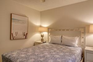 ein Schlafzimmer mit einem Bett und einem Bild an der Wand in der Unterkunft Oceanfront: Beach, Sand and Views at Coral Reef! in North Topsail Beach