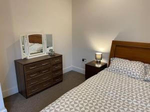ein Schlafzimmer mit einem Bett und eine Kommode mit einem Spiegel in der Unterkunft Home comfort 4 mins from Gatwick! in Horley