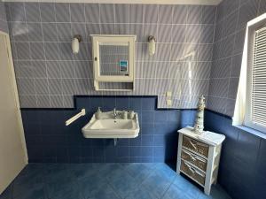 een blauw betegelde badkamer met een wastafel en een spiegel bij Adria Sun Apartments Vodice in Vodice