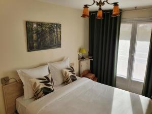 Un dormitorio con una gran cama blanca y una ventana en Chemin vert, en Bayeux