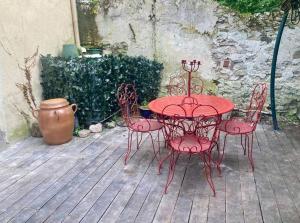 a red table and chairs on a wooden deck at Charmant studio terrasse 25min Aéroport CDG in Saint-Brice-sous-Forêt