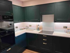 a kitchen with green cabinets and white counter tops at Character cottage in Stamford in Stamford
