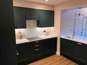 a kitchen with dark green cabinets and a sink at Character cottage in Stamford in Stamford