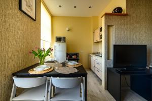 a kitchen with a dining table with chairs and a television at Center apartment Great Amber in Liepāja