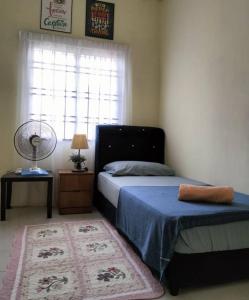 a bedroom with a bed and a window with a fan at Homestay Cikgu in Pasir Gudang