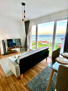 sala de estar con sofá y vistas al océano en Apartamentos LAMAROSA -LAS PLAYAS, en Burela de Cabo