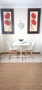 a dining room with a white table and two chairs at Cottage @ Ezulwini in Lobamba