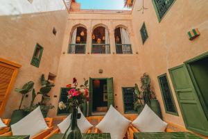 einen Innenhof eines Gebäudes mit Tischen und Blumen in der Unterkunft Hotel & Riad Veridis in Marrakesch