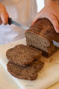 a person cutting a loaf of bread with a knife at Rose e Cioccolato B&B in Borgo Val di Taro +18 photos