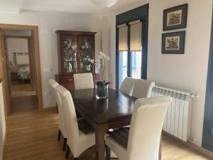 uma sala de jantar com uma mesa de madeira e cadeiras brancas em Modern & cosy Apartment in Jaca Pyrenees Spain em Jaca