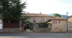 un antiguo edificio de piedra con una puerta y un garaje en Casa de Campoo, en Naveda