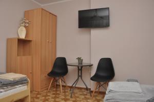 a bedroom with two chairs and a table with a tv on the wall at Apartament Pod Świerkami in Olecko
