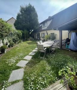 a backyard with a table and chairs and flowers at le prieuré reposant in Notre-Dame de la Mer