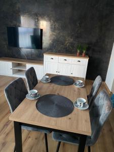 a dining room table with chairs and a television at Apartament Gdańsk Ujeścisko in Gdańsk
