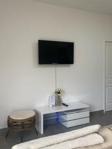 een woonkamer met een tv aan een witte muur bij Logement dans propriété privée 2 in Saint Julien Les Rosiers