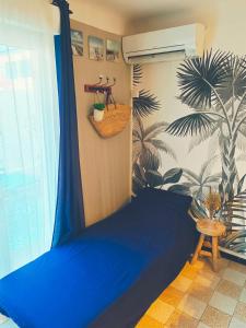 a bedroom with a blue bed and a palm tree mural at Narbonne Studio Lamarobile avec jardin et terrasse proche des Grands Buffets, du centre ville et de la gare in Narbonne