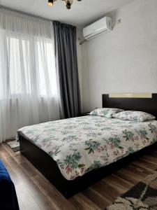 1 Schlafzimmer mit einem Bett mit einer Blumendecke und einem Fenster in der Unterkunft Apartment Alex in Sandanski