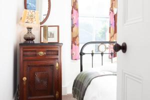 1 dormitorio con 1 cama y vestidor con espejo en Janies Cottage~ Mousehole~Eclectic Interiors & Vintage Charm en Mousehole