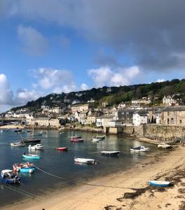 a group of boats in the water near a beach at Janies Cottage~ Mousehole~Eclectic Interiors & Vintage Charm in Mousehole