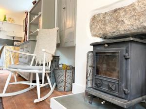 una sala de estar con una estufa antigua y una silla en Janies Cottage~ Mousehole~Eclectic Interiors & Vintage Charm en Mousehole