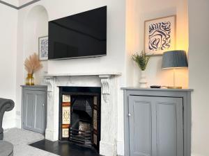 a living room with a fireplace with a flat screen tv above it at Spacious Home Near Seafront & Train Station 5 Bed Sleeps 10- Central Penzance in Penzance