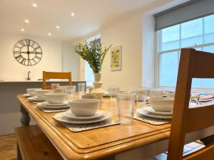 a dining room table with plates and dishes on it at Spacious Home Near Seafront & Train Station 5 Bed Sleeps 10- Central Penzance in Penzance
