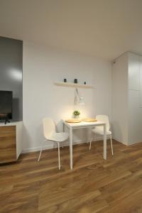 ein weißes Esszimmer mit einem Tisch und 2 Stühlen in der Unterkunft Apartament Wrocław in Breslau