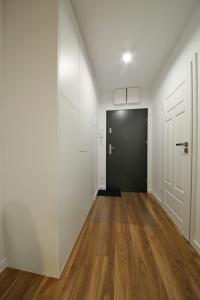 einen leeren Flur mit schwarzer Tür und Holzböden in der Unterkunft Apartament Wrocław in Breslau