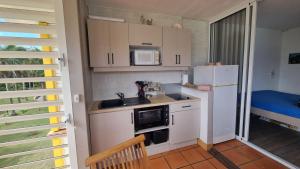 a small kitchen with a refrigerator and a microwave at Le coup de coeur in Saint-François +12 photos