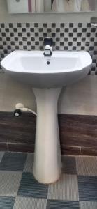 a white sink in a bathroom with black and white tiles at Puneetha home stay hampi in Hampi