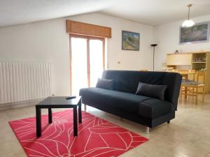 ein Wohnzimmer mit einem schwarzen Sofa und einem Tisch in der Unterkunft Attico mansardato luminoso in Orsogna