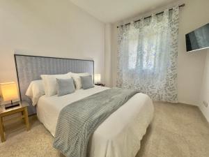 a bedroom with a large white bed and a window at ApartSur® in Bormujos +34 photos
