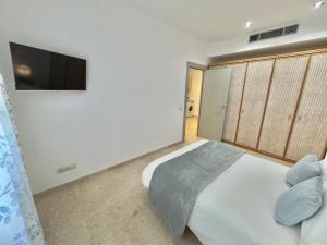 um quarto com uma cama branca e uma televisão de ecrã plano em ApartSur® em Bormujos