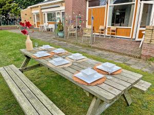een houten picknicktafel met borden en servetten erop bij Beach House Wantveld Noordwijk aan Zee in Noordwijk aan Zee